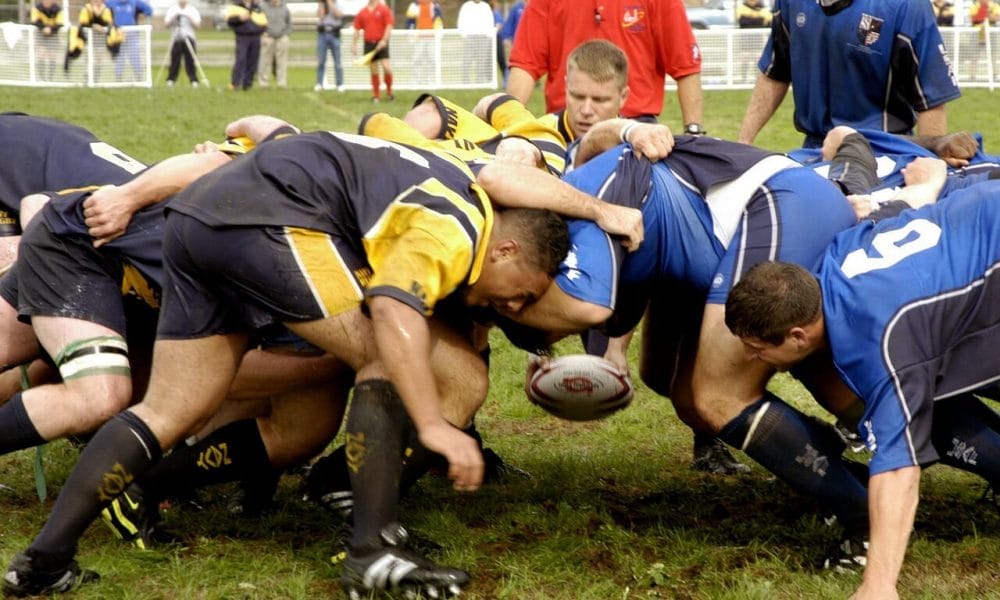 grupo de hombres jugando y peleando por el balón en un partido de rugby