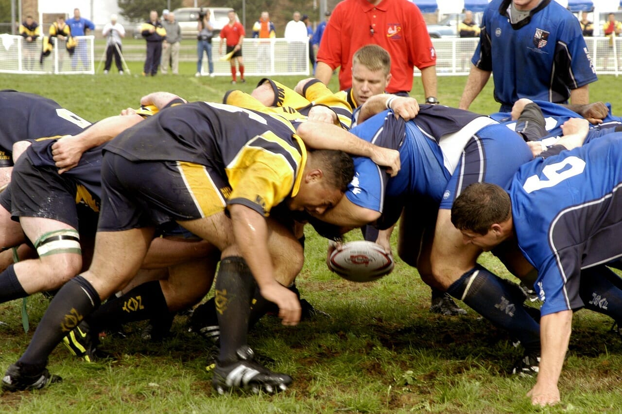 grupo de hombres jugando y peleando por el balón en un partido de rugby