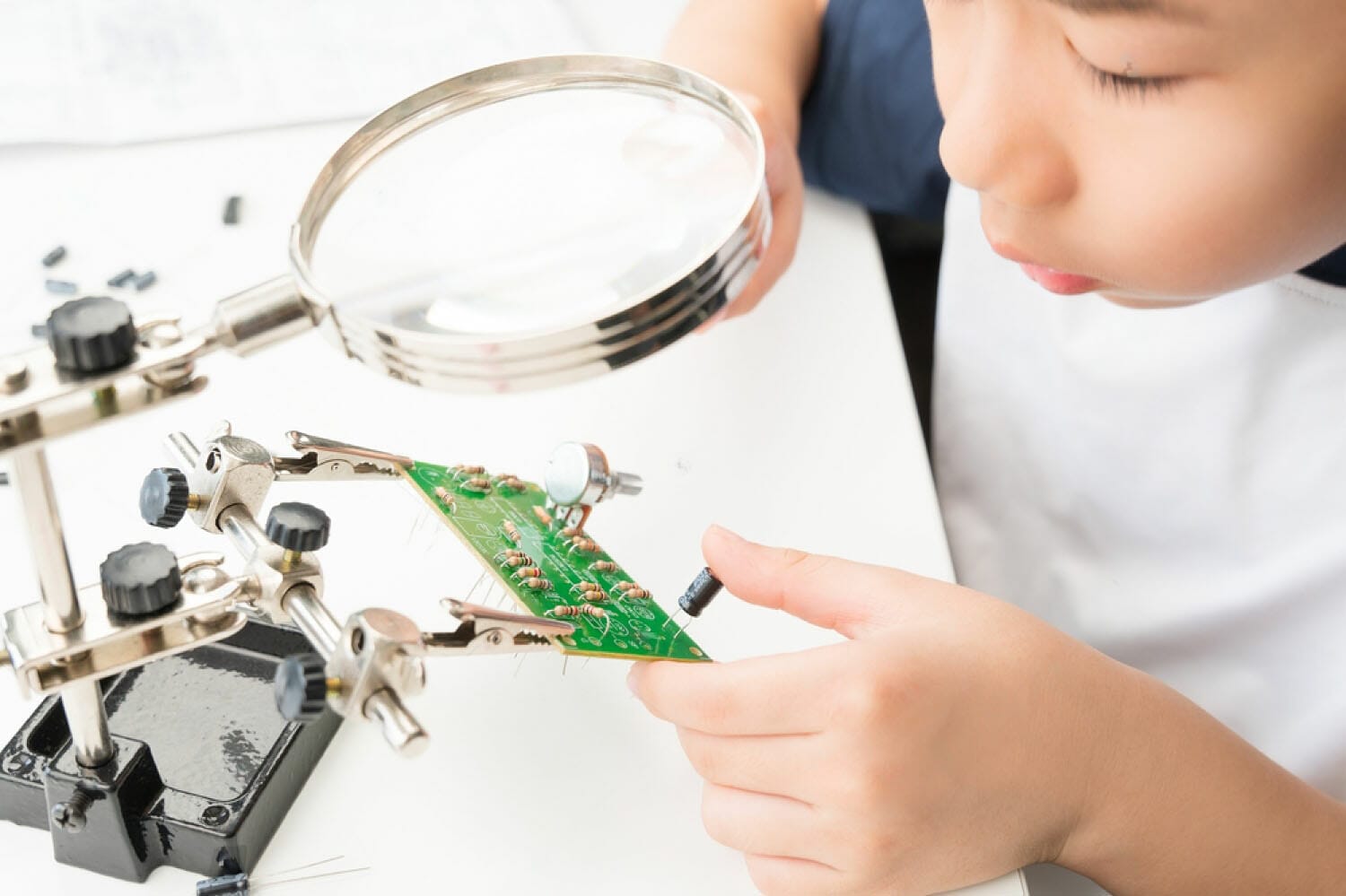 niño mirando a través de una lupa un circuito electrónico en una placa